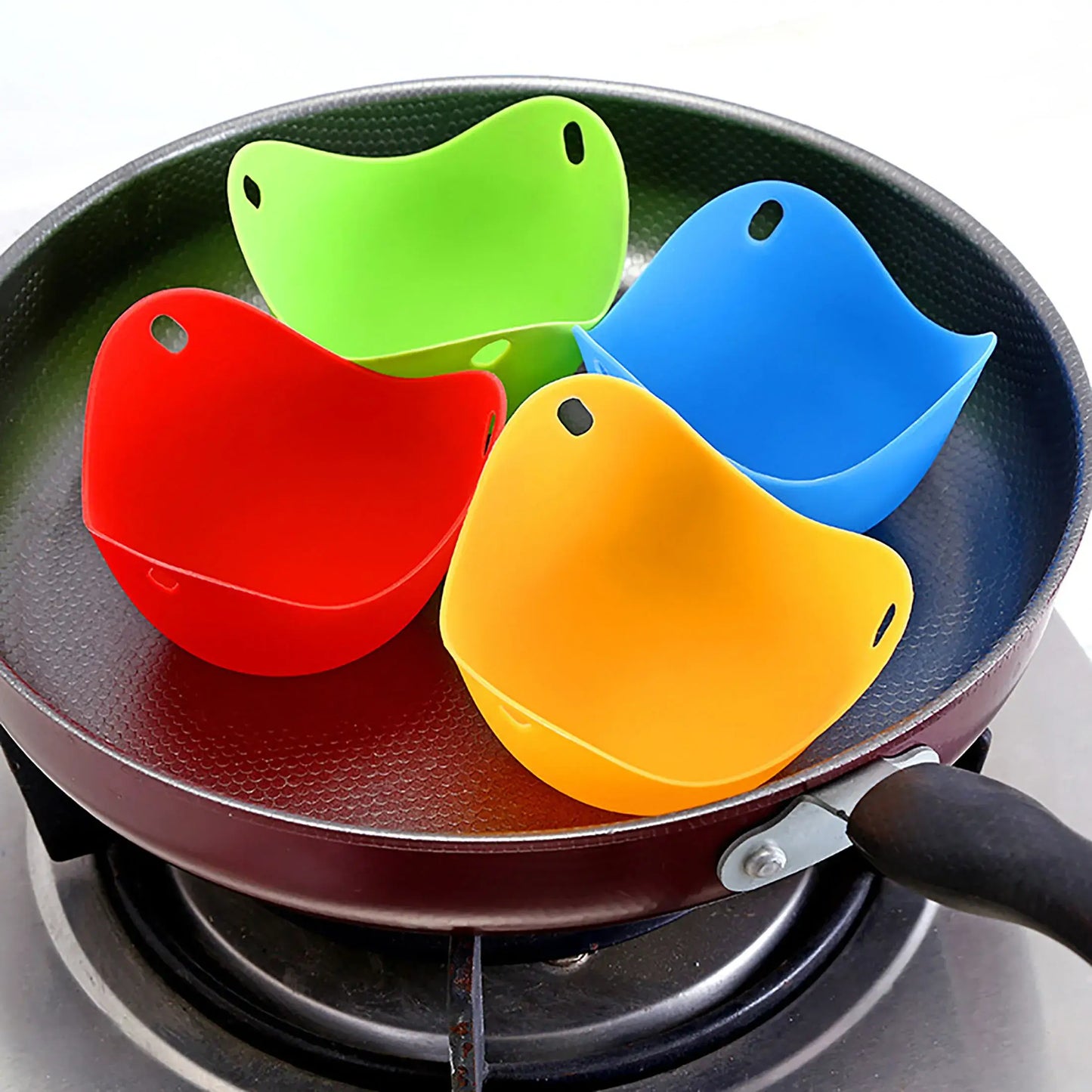 Colorful silicone egg poacher cups in a frying pan for cooking eggs on stovetop, microwave, or air fryer.