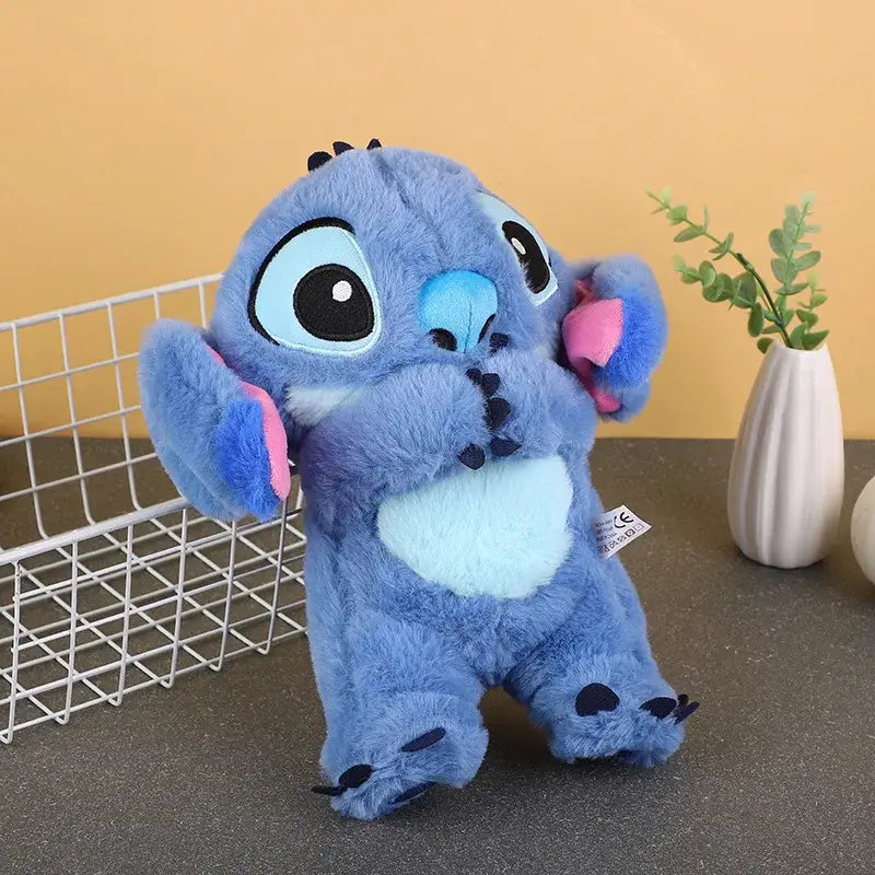 Cute blue Stitch plush doll with pink ears and big eyes on a table, perfect for children and baby gifts.