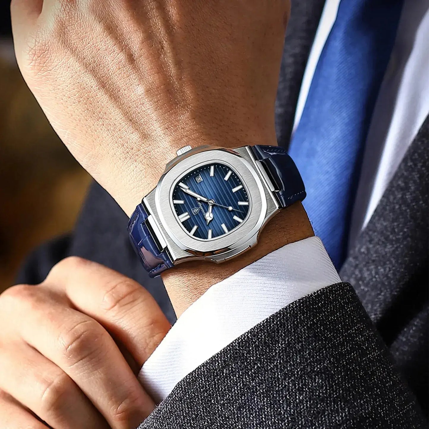 POEDAGAR luxury square men's watch with blue dial and leather strap, worn on wrist with formal attire.