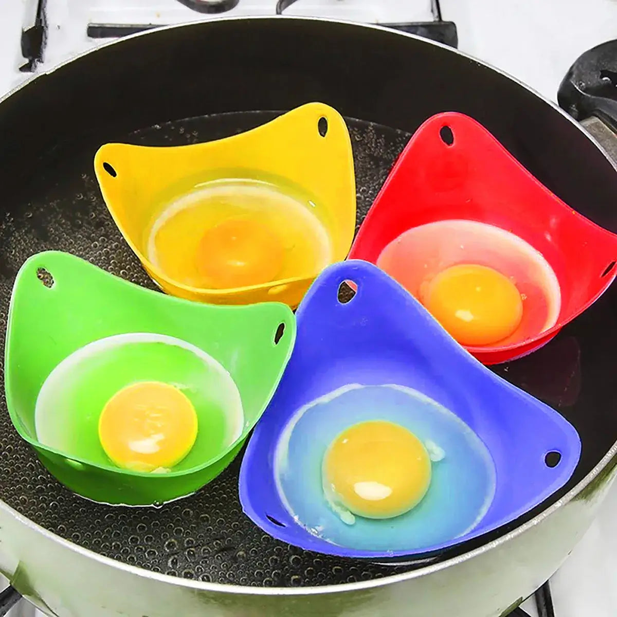 Colorful silicone egg poacher cups with eggs cooking on stovetop.