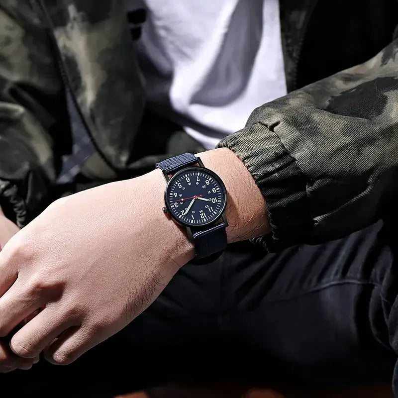 Stylish men's quartz watch with luminous hands on wrist, set against a camo jacket background. Big dial, waterproof design.