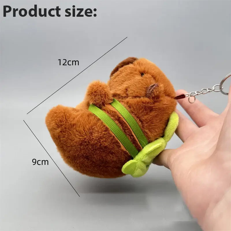 Cute brown capibara plush keychain with green turtle backpack, showcasing product size of 12cm by 9cm.