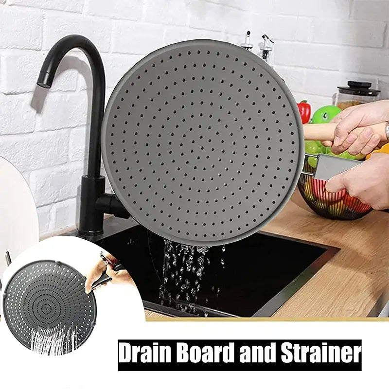 Silicone kitchen splatter screen with handle being used as a drain board and strainer over a sink.