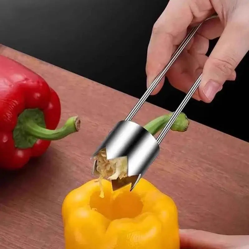 Stainless steel vegetable core remover tool extracting core from yellow bell pepper on wooden surface.