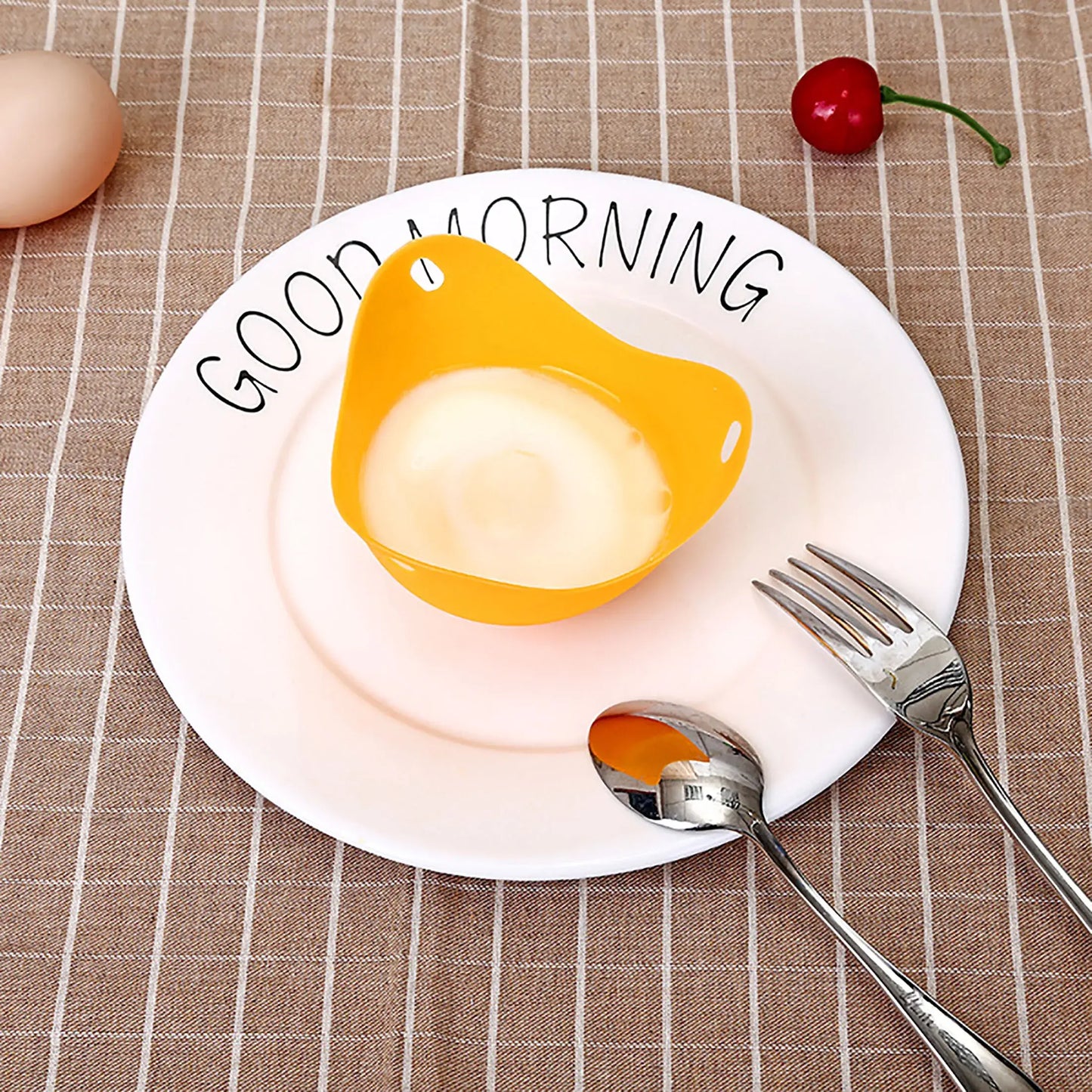 Silicone egg poacher cup on a plate with cutlery, perfect for cooking eggs in microwave, air fryer, or stovetop.