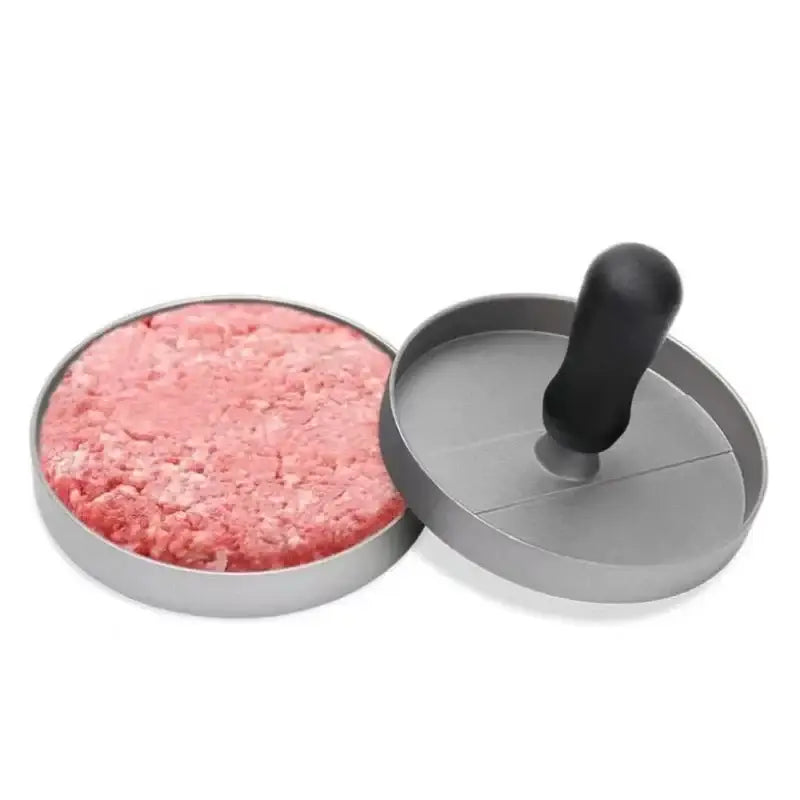 Non-stick aluminum burger press with removable handle and perfectly shaped raw patty for grilling.