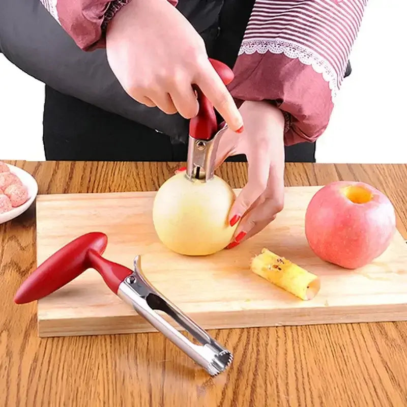 Stainless steel apple corer in use, removing core from a white apple on a wooden cutting board, with a pink apple nearby.