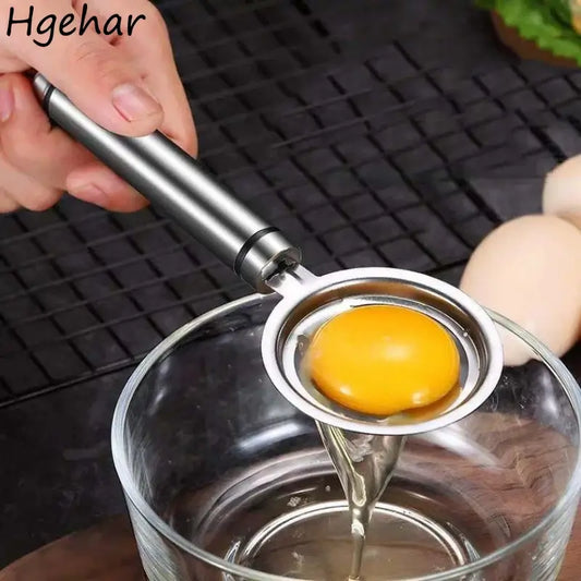 Stainless steel egg separator tool in use, effortlessly separating yolk from egg white in a glass bowl.